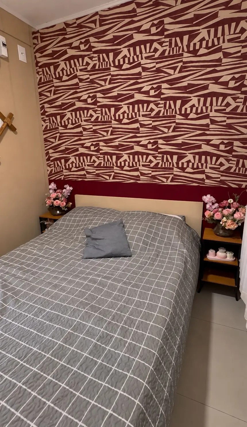 Quarto 2, com cama de casal, colcha cinza xadrez e parede geométrica em vinho e bege