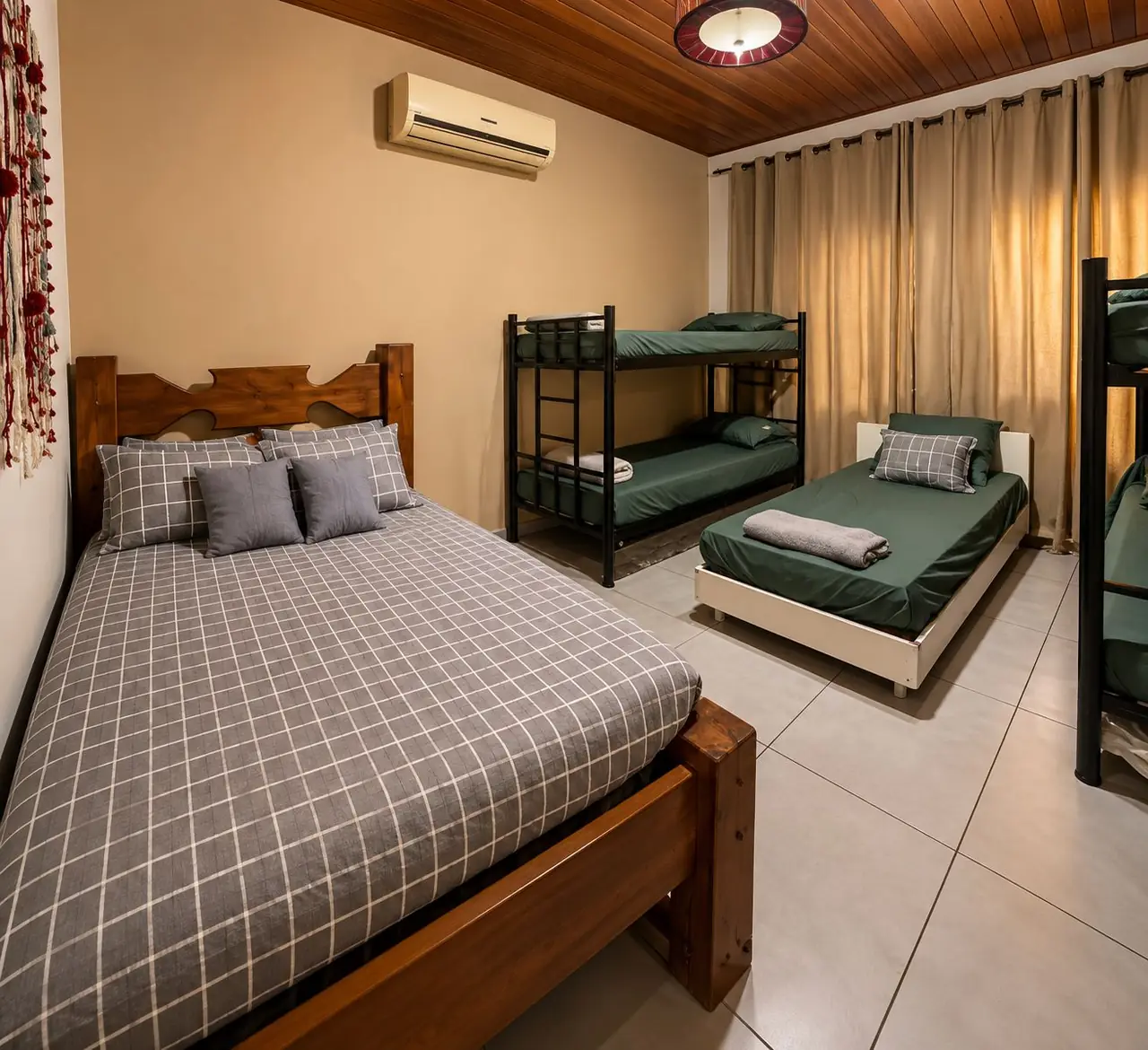 Quarto 5, o maior, com cama de casal de madeira, dois beliches, cama de solteiro e teto de madeira